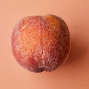 A detailed view of a fresh, ripe peach on a pink background. Perfect for healthy lifestyle themes.
